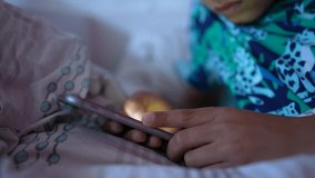 Child scrolling through phone screen in morning bed
