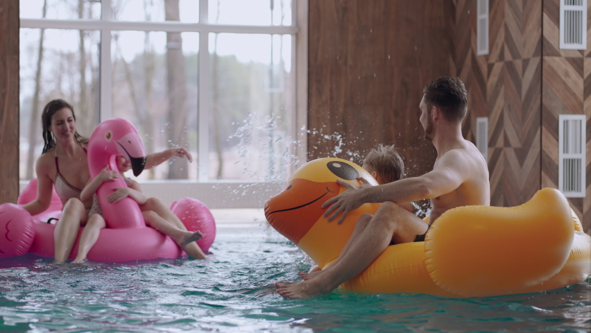 mother and father are resting with children in family water park, little boy and girl with parents are swimming
