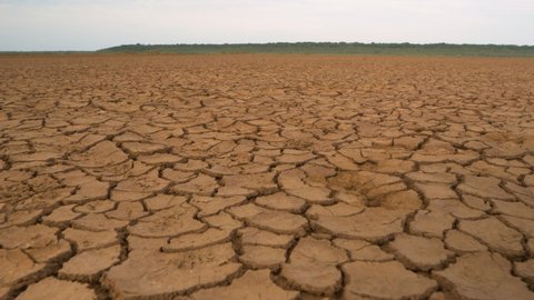 CLOSE UP: Big area of cracked soil caused by long draught. Brown desiccated land with ground cracks and no vegetation. Dry landscape with crack pattern caused by lack of water.