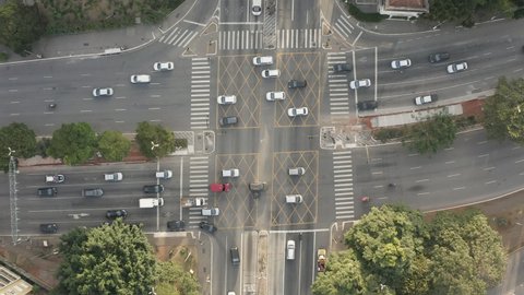 Aerial footage birds eye view of intersection of large avenues during the day in Sao Paulo. Cars and buses driving