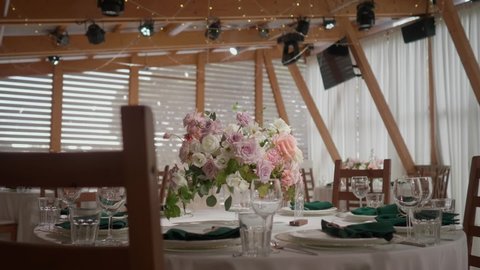 A dining table decorated with flowers in a bright and beautiful hall before the wedding. High quality FullHD footage