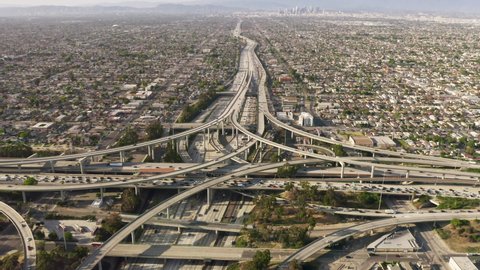 Business center of Los Angeles City at golden sunset, USA. Drone aerial of cars driving by multilevel highway. Urban cityscape 4K. Busy traffic highway transportation at downtown Los Angeles streets