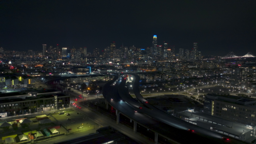 Epic aerial panorama of cinematic San Francisco downtown at night. Scenic modern skyscrapers night illumination, Busy city traffic at night on curving highway with cityscape on background, USA 4K view