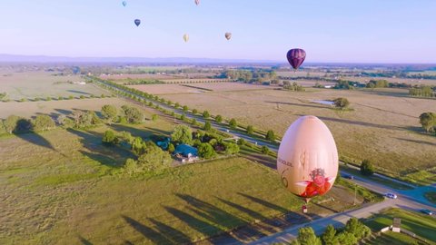 Milawa, VIC, Australia - 26-Mar-2022 - Hot Air Balloons at the King Valley Balloon Fiesta at sunrise. Shot pans upwards to reveal the balloons in flight.