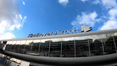 Eindhoven, Netherlands, January 30, 2022: PAN SLOW MOTION SHOT - Eindhoven Airport Terminal. Passengers in front of Modern architecture Eindhoven airport.