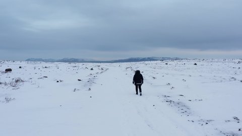 Lone adventurer walking in vast open white snow covered back country in Iceland