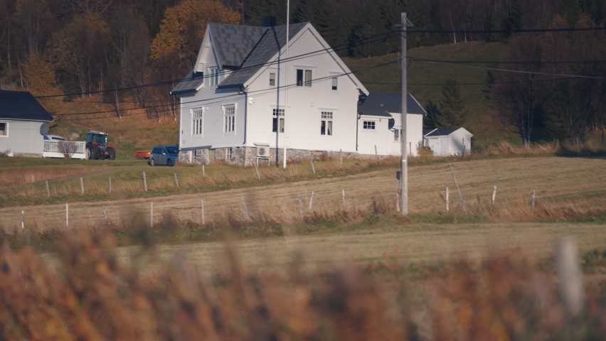 A farm in the Norwegian countryside. Hay bales are arranged on the field. Slow-motion. pan follow.