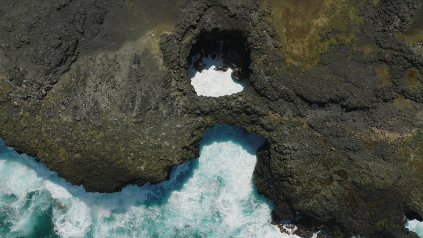 Pont Naturel. Mauritius. Aerial top view of waves break on rocks in a blue ocean. Royalty-Free Stock Footage #1089533571