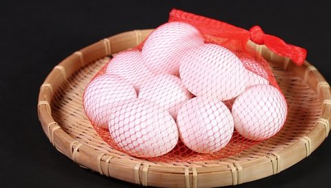Fresh chicken eggs in red plastic net on a colander rotating
