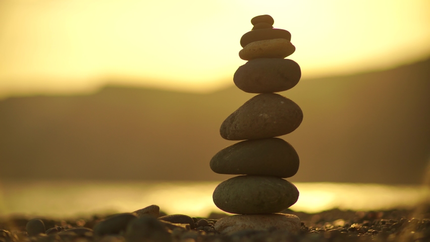 Zen stones on the sea beach. Silhouette of a cairn on a pebble beach at sunset. Abstract bokeh with sea in the background, meditation, spa, harmony, tranquility, balance concept Royalty-Free Stock Footage #1089534153