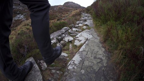 A man with backpack hiking up old Roman steps in Snowdonia Rhinogydd mountains in Wales