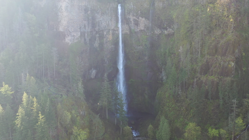 Clouds drift over a scenic waterfall plunging over 500 feet into the Columbia River Gorge, Oregon. This narrow canyon, with the Columbia River flowing through it, separates Oregon and Washington.