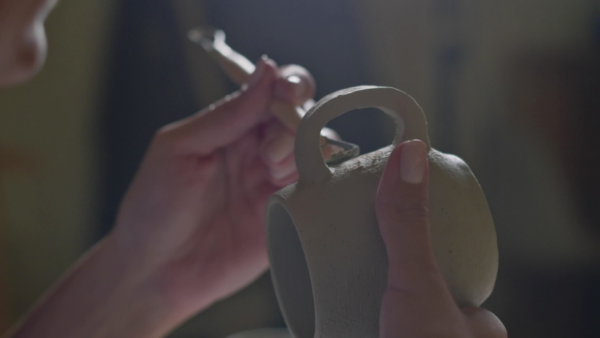 Close up of female potter using tool to finishing to making ceramic clay cup in potter studio