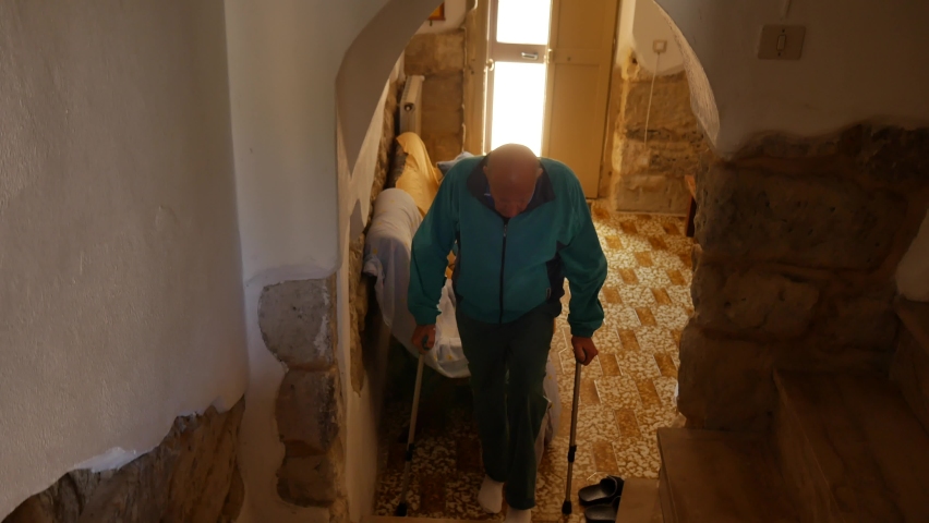 Elderly man falling on crutches from the stairs in the house, losing his balance by tripping on crutches and falling to the ground. domestic injury.