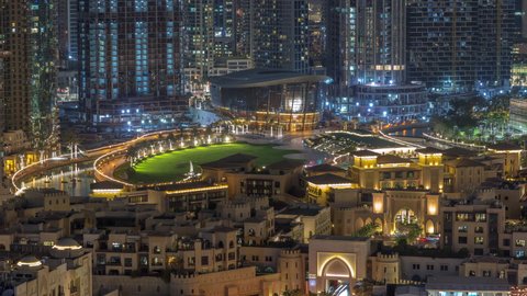 Aerial view to illuminated traditional houses of old town island night timelapse from above. Dubai downtown with fountains area near mall and souk. Park with green lawn