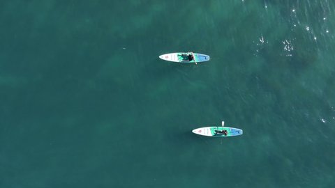 April 19, 2022. Sozopol, Bulgaria. Couple on stand up paddle board at blue sea. People rowing on Red paddle sup board in sea. Aerial view