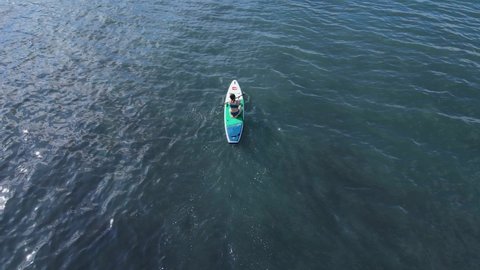 April 20, 2022. Sozopol, Bulgaria. Woman on stand up paddle board at blue sea. Relax on Red Paddle sup board in sea. Aerial view