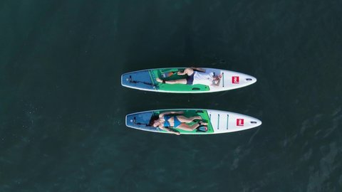 April 19, 2022. Sozopol, Bulgaria. Couple on stand up paddle board at blue sea. People relaxing on Red paddle sup board in sea. Aerial view