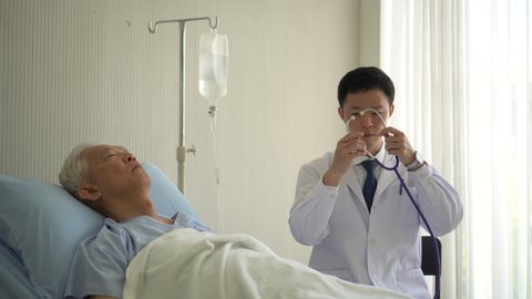 Asian doctor checking senior elderly patient heart pulse rate while admit in hospital