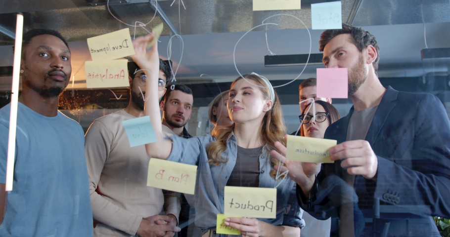 Diverse peole standing in front of tasks and to-do notes and discussing plan. Teambuilding of multiethnic colleagues. Coworkers brainstorming in office. Business concept. Management strategy