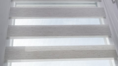 The mechanism of tnaninny roller blinds close up. Duo window roller system day and night. Close up on roller blinds indoors.