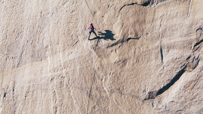 Woman confidently rock climbs mountain, fitness lifestyle. Extreme sport on outdoor adventure trip. Athletic professional sportsmen working with ropes on the steep cliff on sunny summer day, Yosemite