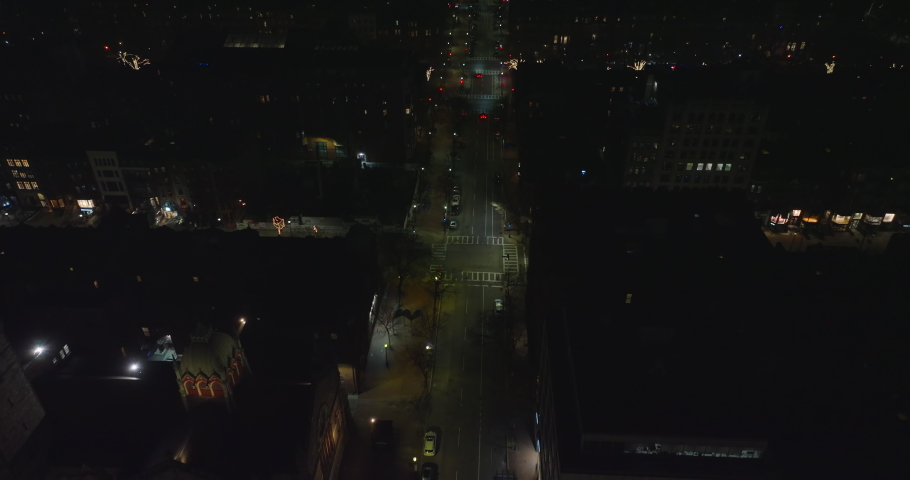 High angle view of street in urban neighbourhood. Tilt up reveal of night cityscape with reflections on water surface. Boston, USA