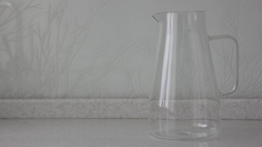 In an empty two-liter carafe, a man pours his hand a few freshly frozen large raspberries to make cool lemonade. Berries are applied to a glass container for the preparation of berry juice