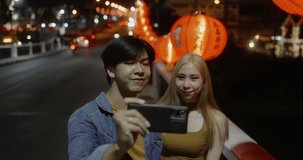 Young Asian couple make a video live streaming on social network by phone in Chinese new year lantern festival.