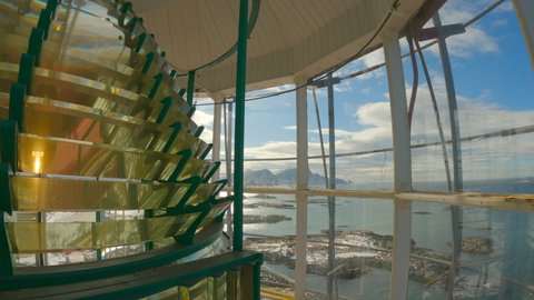Static shot inside the Andenes lighthouse lantern room with the lens spinning looking out over the beautiful harbor and distant mountains