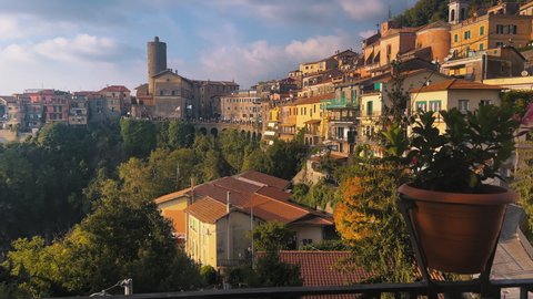 Wide shot showing beautiful old buildings of Nevi City lighting by sunset with tower in background,Italy