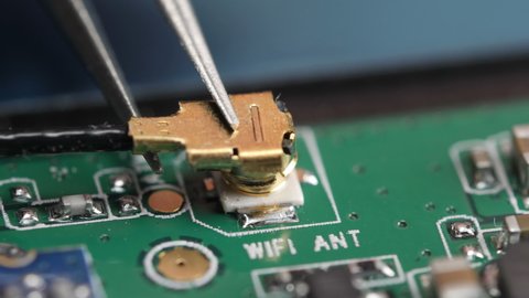 Connecting antenna on motherboard with pliers.
Macro video showing a wifi antenna on electronic circuit board.