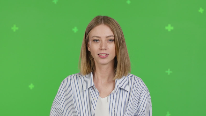 Portrait of woman covering her mouth with her hand. Green screen background