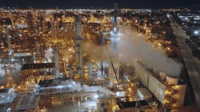 Scenic panorama of steam vaporizing above the big plant with chimneys and metallic facilities. Aerial view of the manufacturing area at the outskirts of the city. High quality 4k footage
