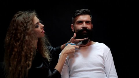 Cutting long beard. Barbershop or hairdresser. Sexy woman hairdresser cuts beard with scissors. Man with long beard, mustache and stylish hair.