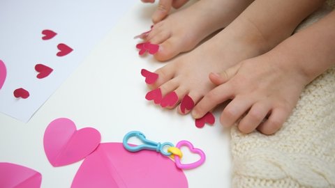 Child playing with adhesive tape paper, funny pedicure with small hearts