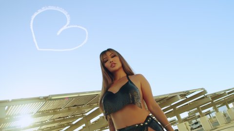 Sexy girl posing against the sky with a big heart in the sky. Slow motion. Beautiful woman in summer in Santa Monica