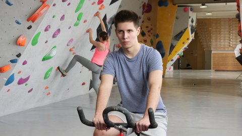 Sports guy on an exercise bike in a climbing hall. High quality 4k footage