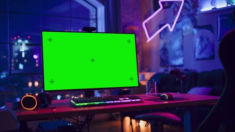 Gaming at Home: Empty Gaming Station with Player's Personal Computer with Green Screen Chroma Key Display Standing on a Wooden Desk in Stylish Loft Apartment with Neon Lights. Arc Shot.