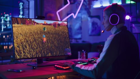 Excited Female Gamer Playing MMORPG Video Game on Her Personal Computer in Which Players Fight in a Tournament. Room and PC with Neon Led Lights. Stylish Young Woman in Cozy Room at Home.