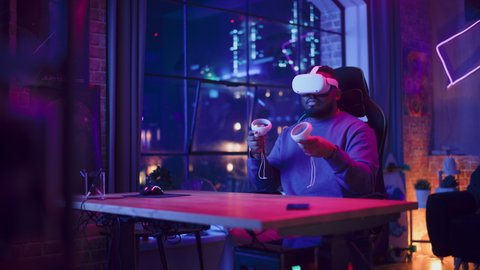 Stylish Man Using Virtual Reality Headset with Controllers at Home in Loft Apartment. Young African American Male Browsing Online, Spending Time in VR Digital Office. POV from Screen Perspective.