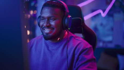 Professional Black Gamer Playing Online Video Game on Computer. Close Up Portrait of Young Man in Headphones Battling in PvP Tournament with Other Players, Talking with Team on Microphone.