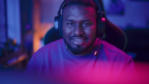 Professional Multiethnic Gamer Playing Online Video Game on Computer. Close Up Portrait of Young Black Man in Headphones Battling in PvP Tournament with Other Players, Talking with Team on Microphone.