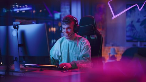 Successful Gamer Winning in Online Video Game on Computer. Portrait of Young Stylish Man in Headphones Playing PvP Tournament with Other Players, Talking with Team on Microphone.