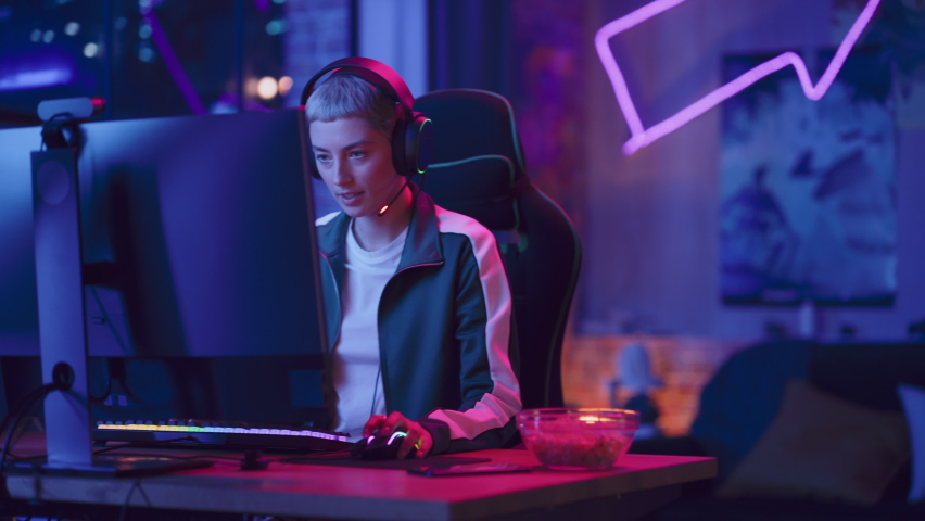 Excited Female Gamer Playing Online Video Game on Computer. Portrait of Slightly Stressed Woman in Headphones Battling in PvP Tournament with Other Players, Talking with Team on Microphone. Royalty-Free Stock Footage #1089581955