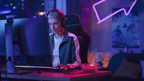 Excited Female Gamer Playing Online Video Game on Computer. Portrait of Slightly Stressed Woman in Headphones Battling in PvP Tournament with Other Players, Talking with Team on Microphone.