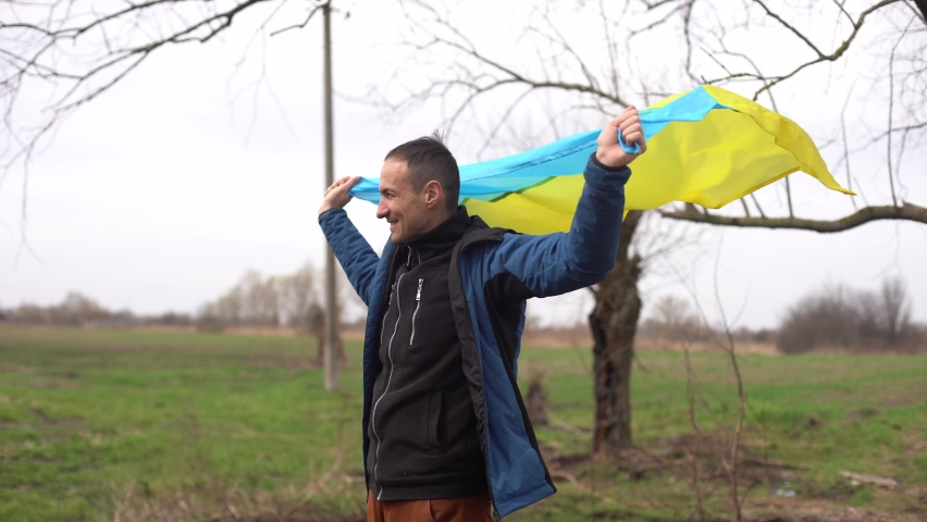 man with the flag of Ukraine near the burnt tree