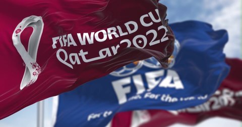 Doha, Qatar, April 2022: Flags with Qatar 2022 World Cup logo and FIFA waving in the wind. The event is scheduled in Qatar from 21 November to 18 December 2022. Seamless loop in slow motion. 4K