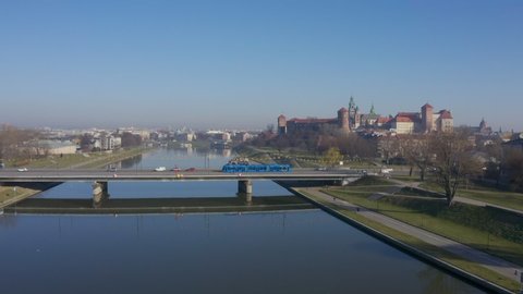 Blue tram rides over Grunwaldzki bridge at Vistula river,  Wawel castleat the background in Cracow ( Krakow), Poland. Static video footage.  relaxed morning mood aerial video
