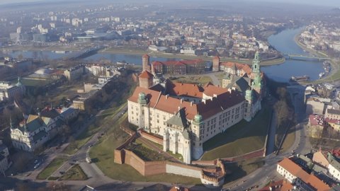 Wawel castle in Krakow Poland. Aerial drone camera flies over the roofs of  panorama of the city, bridge and river Vistula and Grunwaldzki bridge in the dawn sunbeams and fog from above view.